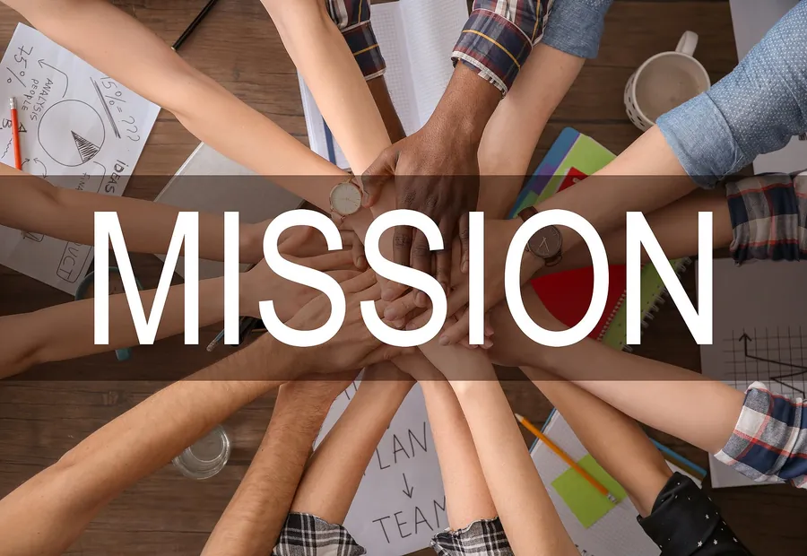 Team members joining hands around the word Mission